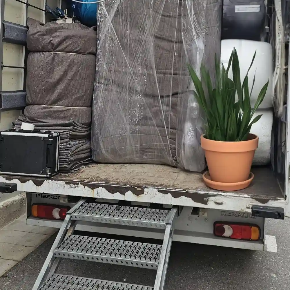 Arrière du camion chargé de meubles emballés, avec une plante en pot