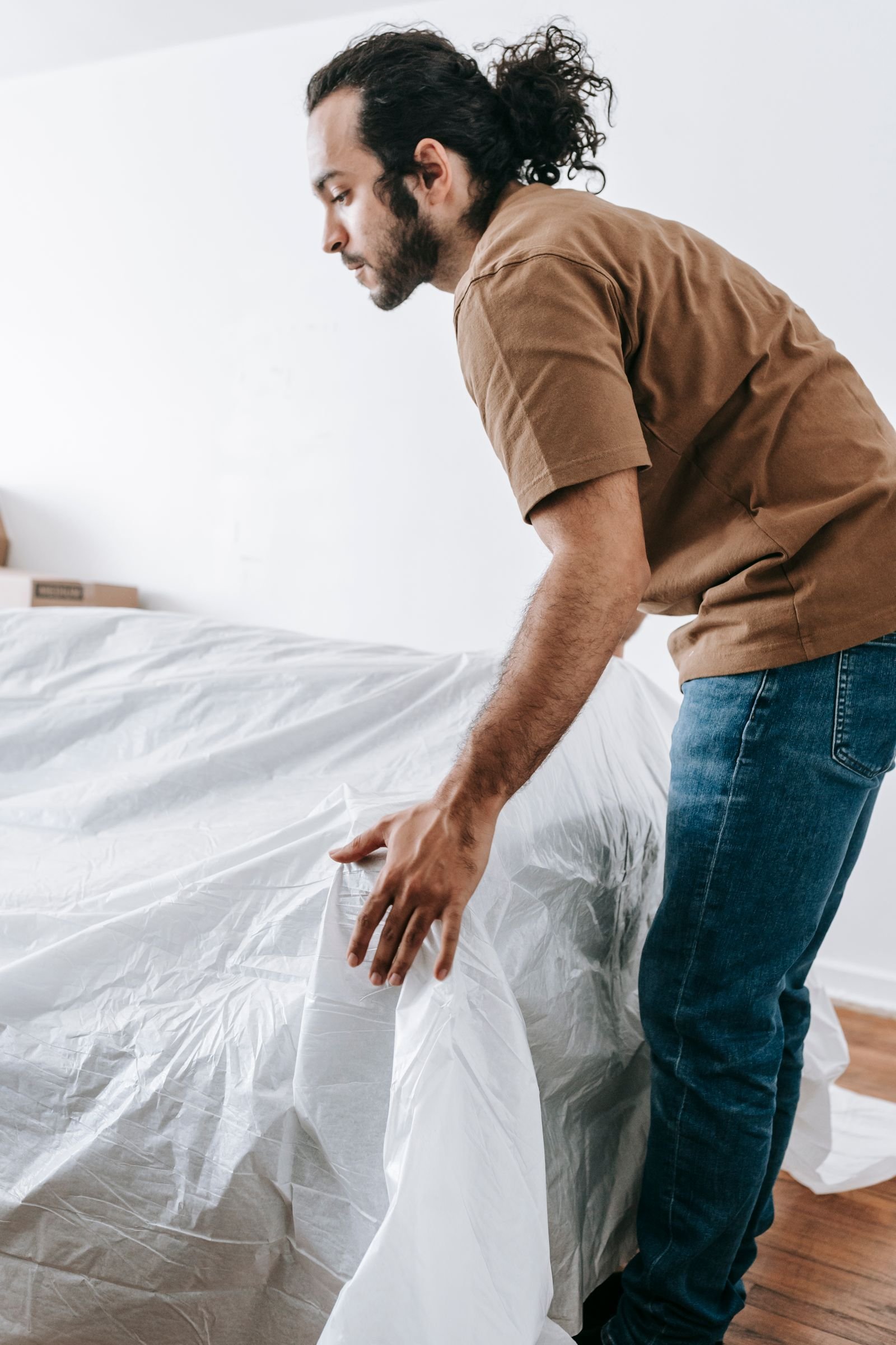 Un homme couvre un canapé d’une housse de protection