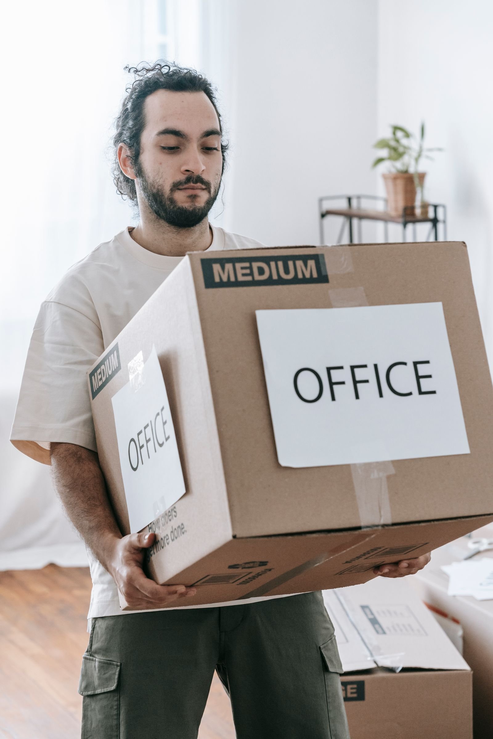 Un homme porte un carton de déménagement étiqueté bureau