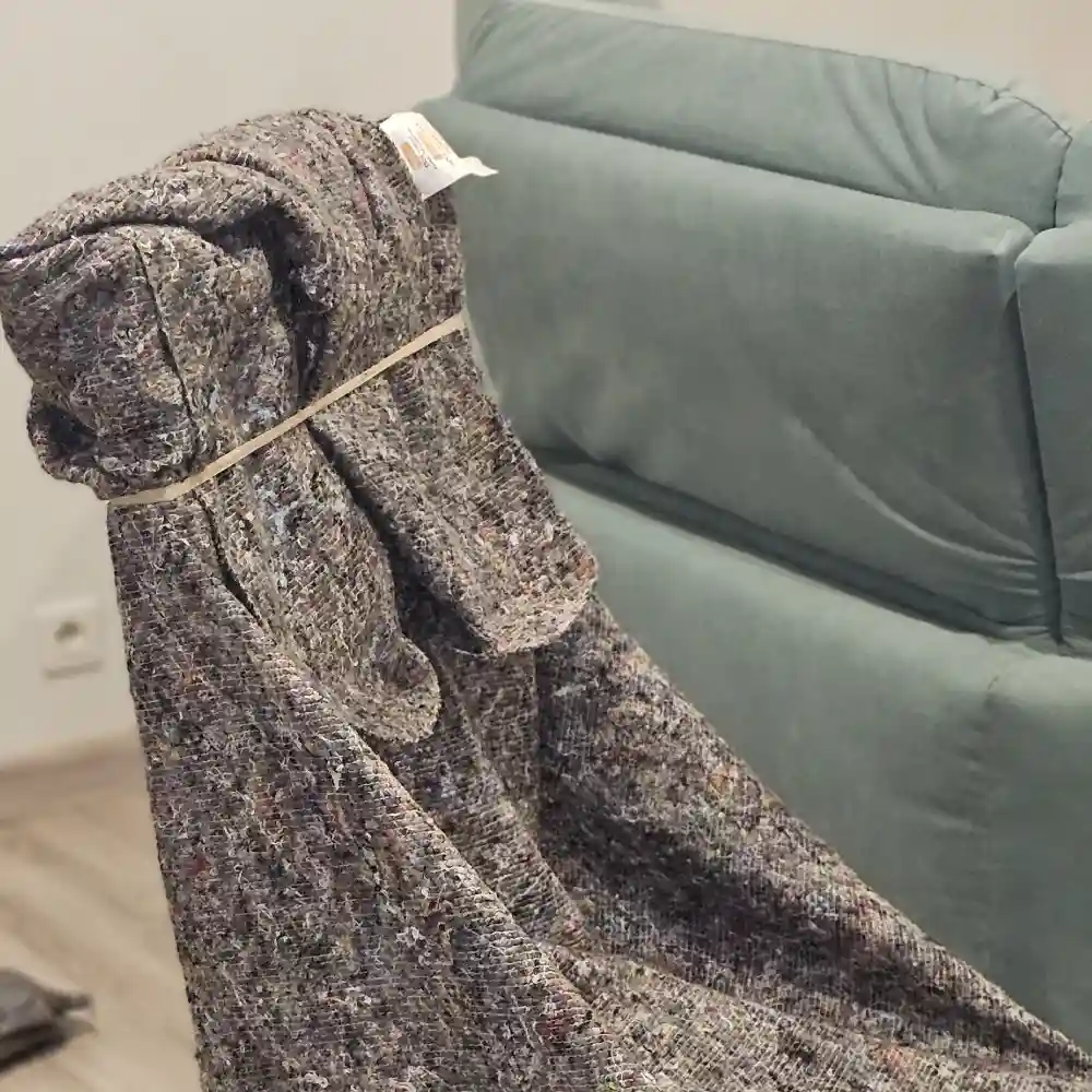 Fauteuil protégé par une couverture ficelée, à côté d’un canapé
