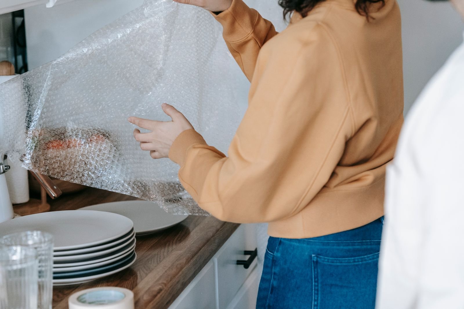 Une femme emballe des assiettes dans du papier bulle